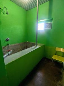 a green bathroom with a tub and a yellow chair at Pelican Spa in Truth or Consequences