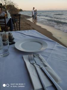 Una mesa con un plato, cuchillo y tenedor en la playa. en DIAS APPARTMENT, en Artemida 4 fotos más