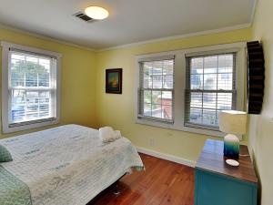 een slaapkamer met gele muren en een bed en ramen bij CB Sunshine Cottage in Carolina Beach +28 foto's