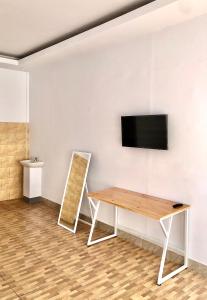 MambatにあるLangit Biru Guest Houseのテーブルと壁にテレビが掛かっている部屋 +4枚の写真