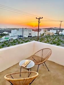 two chairs and a table on a balcony with a sunset at Casa Kallisti Suites in Pirgos