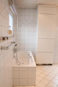 ein weißes Bad mit einer Badewanne und einem Fenster in der Unterkunft Ferienwohnung Rheda-Wiedenbrück in Rheda-Wiedenbrück