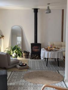 a living room with a fireplace and a table and a stove at La Petite Maison de Locarn in Locarn +6 photos