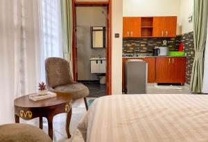 a bedroom with a bed and a table and a kitchen at iKHAYA RESIDENCES MUNYONYO in Kampala