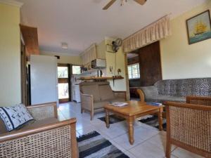 a living room with couches and a table and a kitchen at North Lodge Cottages in Durban