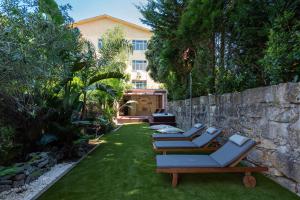a row of chaise lounges on a lawn next to a wall at BmyGuest - The Marquis Luxury Garden Apartment in Porto