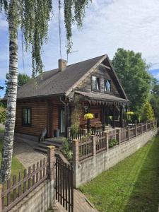 a wooden house with a fence in front of it at Brīvdienu māja pie Gaujas in Siguļi