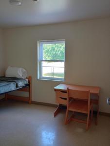 a bedroom with a bed and a desk and a window at The Saints Suites at NCCC in Saranac Lake +13 photos