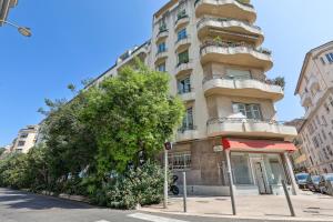 een hoog gebouw met een boom ervoor bij Lavie Maison Hot Tub Seaside Studio in Nice