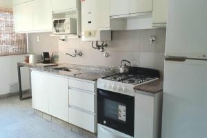 a kitchen with white cabinets and a stove top oven at Dpto Vintage Inés in Guaymallen