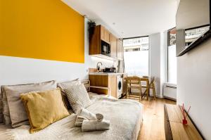 een woonkamer met een bank en een gele muur bij Lavie Maison Hot Tub Seaside Studio in Nice