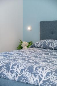 a bed with a blue and white comforter and a plant at Costabella Rooms in Deiva Marina