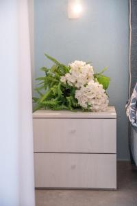 a dresser with a bouquet of white flowers on it at Costabella Rooms in Deiva Marina
