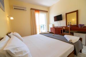a bedroom with a large bed with a desk and a mirror at Iraklis Hotel in Mytikas