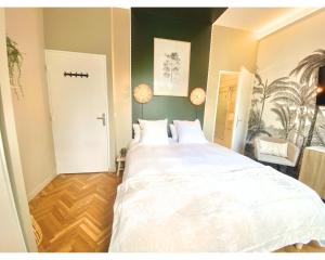 Un dormitorio con una cama grande con sábanas blancas. en Chambre Cosy chez l habitant avec salle de bain et jardin privé, en París