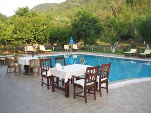a table and chairs next to a swimming pool at Doga Apartments in Kayakoy