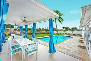 Un patio con mesa y sillas y una piscina. en NEW Waterfront Tropic Oasis - Heated Pool, Canal, Dock, Air Hockey, en Boynton Beach