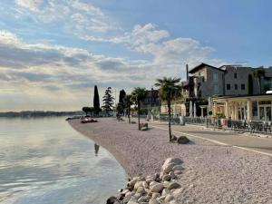 a beach with trees and buildings next to the water at Lake Garda Lovers Luxury in Peschiera del Garda