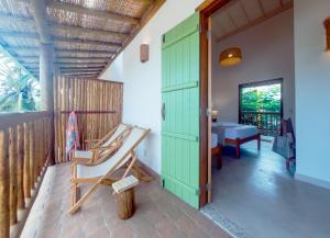 a room with a green door and a chair at Jardim Cumuru - Suítes in Cumuruxatiba