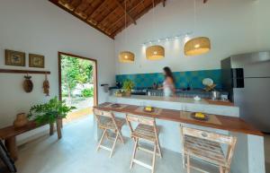 a kitchen with a counter with stools and a refrigerator at Jardim Cumuru - Suítes in Cumuruxatiba
