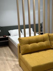 a bed with a yellow couch in a room at Apartments ABC in Mostar
