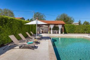 a pool with lounge chairs and an umbrella next to a hedge at Villa Anastasia in Sveti Petar u Šumi