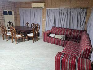 a living room with a couch and a table and chairs at ghroob farmhouse villa in Al Ḩamrānīyah