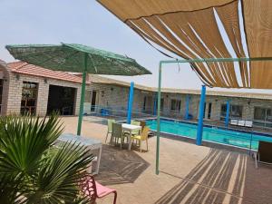 a patio with tables and umbrellas next to a pool at ghroob farmhouse villa in Al Ḩamrānīyah +20 photos