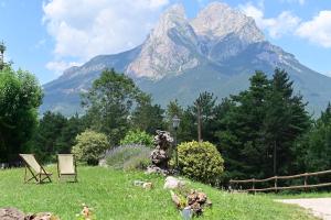 a mountain in the distance with a chair in a field at L'indret del Pedraforca Adults Only in Saldés