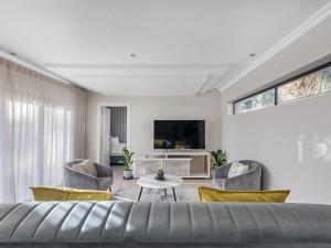 a living room with a couch and chairs and a tv at Self Checkin - Luxury Tranquil Apartment in Guesthouse in Johannesburg