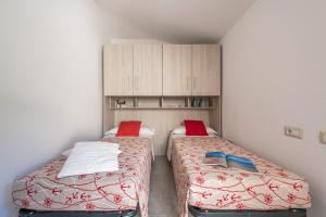 two beds in a small room with cabinets at Casa Marco Sardinia Domus in Cala Gonone