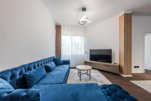 a living room with a blue couch and a tv at The City Center Penthouse by PS in Durrës
