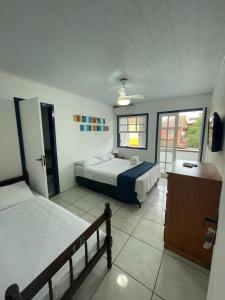 a bedroom with two beds and a large window at Brothers Suites Centro Búzios in Búzios