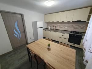 a kitchen with a wooden table and a refrigerator at GMV House in Călimăneşti
