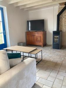 a living room with a tv and a couch and a table at Grand gîte Ô joli Albizia - Maison avec studio indépendant et spa privatif pour 8 à 10 personnes in Péault