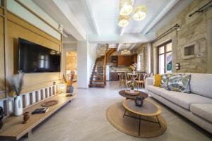 a living room with a couch and a tv at Asion Lithos Villas & Suites with Private Pools in Kato Asites
