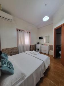una camera da letto con un grande letto bianco con cuscini blu di B&B Il Girasole a SantʼAnna Arresi