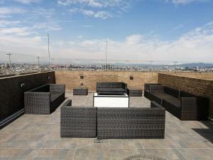 a rooftop patio with wicker furniture and a view of a city at Nice flat in financial heart of Bogotá in Bogotá