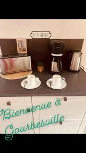 a counter top with two cups and a coffee maker at Maison vacance proche ste mère église in Picauville