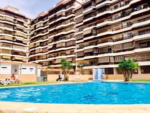 a swimming pool in front of a large apartment building at Jardín Canario Primera línea de Playa in Los Cristianos