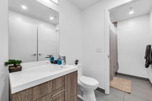 a white bathroom with a toilet and a sink at Deluxe 1BR Suite with bird's eye CN Tower Views in Toronto +76 photos