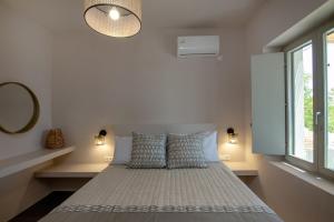 a bedroom with a bed with two pillows and a window at Ohana suite Tinos in Arnados