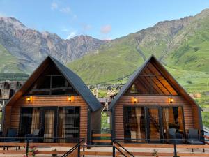 a log cabin with mountains in the background at Outdoor Cottages Kazbegi in Kazbegi