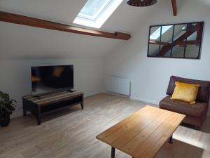 a living room with a couch and a tv and a table at Au 112, maison d'hôtes meublée in Estrées-Saint-Denis