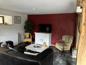 a living room with a black couch and a tv at Ferme 1883 gîte in Lierneux