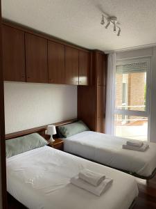 a bedroom with two beds and a window with a window at Apartamento con vistas al mar playa Berria-Santoña in Santoña
