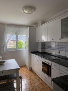 a kitchen with white cabinets and a table and a window at Apartamento con vistas al mar playa Berria-Santoña in Santoña +22 photos