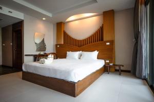 a bedroom with a large bed with a wooden headboard at Dusit Buncha Koh Tao by Riya Group in Ko Tao