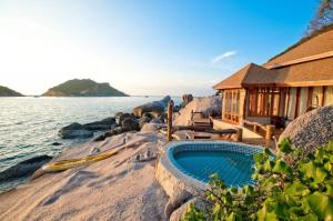 a house with a swimming pool next to the water at Dusit Buncha Koh Tao by Riya Group in Ko Tao