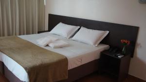 a bed with a white comforter and pillows at Pinheiros Hotel in Goiânia